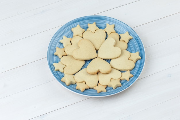 Free photo cookies in a plate on a wooden background. high angle view.