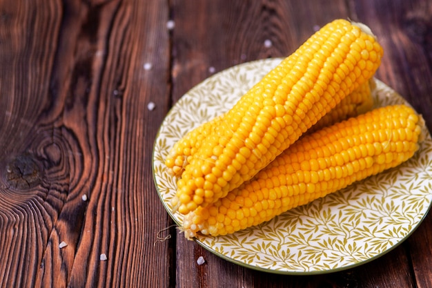 Free photo corn in a plate on a dark wooden table. high angle view.