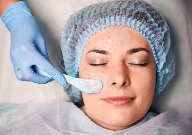 Free Photo cosmetologist hand applying cosmetic mask on woman face