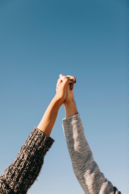 Free photo couple holding hands with sky in background