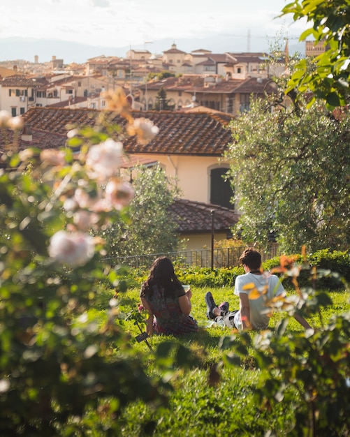 Foto gratuita coppia seduta sull'erba con firenze in