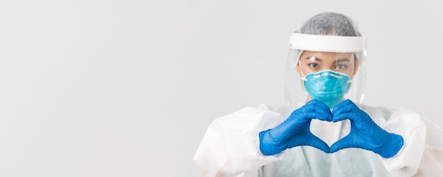 Free photo covid-19, coronavirus disease, healthcare workers concept. close-up of confident and caring asian female doctor in personal protective equipment, showing heart gesture to patients.