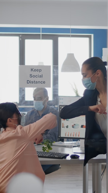 Foto gratuita colleghi che toccano il gomito per evitare l'infezione con il team aziendale del coronavirus che indossa una maschera medica...