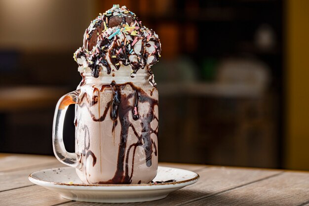 Creamy vanilla milky shake with chocolate sauce in a white saucer