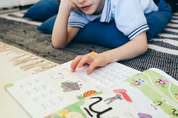 Free Photo crop boy reading textbook on floor