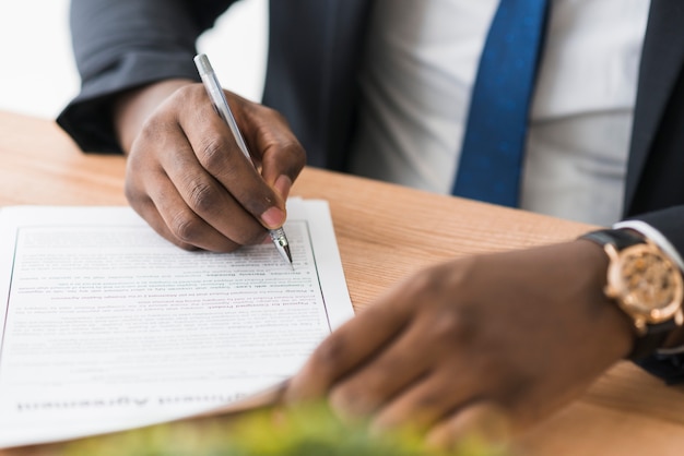 Crop ethnic businessman signing papers