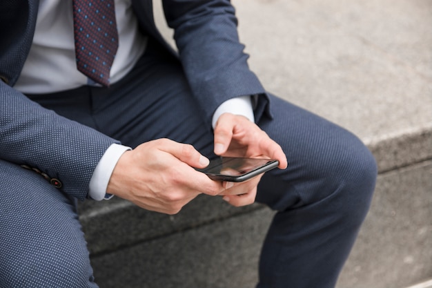 Free photo crop guy in suit browsing smartphone on street