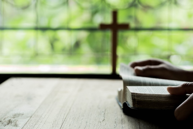 Free photo crosses that open above the bible on a wooden table