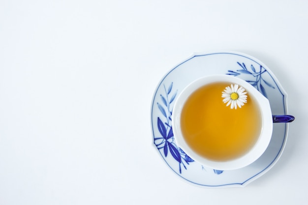 Free photo a cup of chamomile tea on a white table. top view.