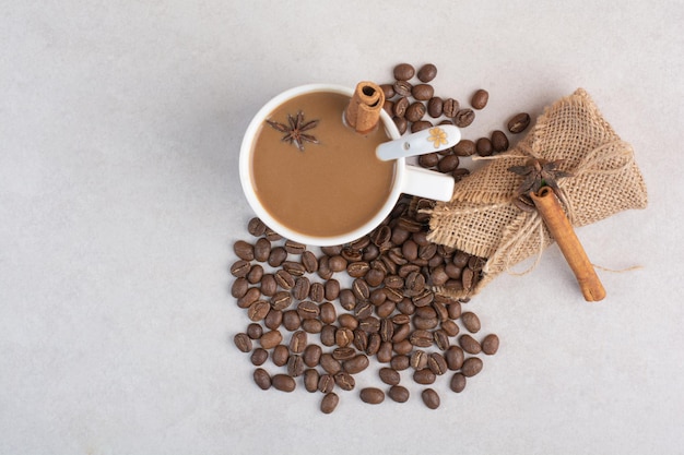 A cup of coffee with cinnamon sticks and coffee beans on marble background. High quality photo