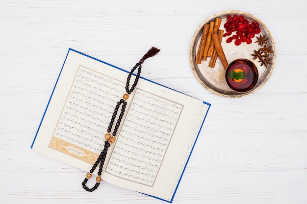 Free photo cup of tea near spices on tray and book with beads