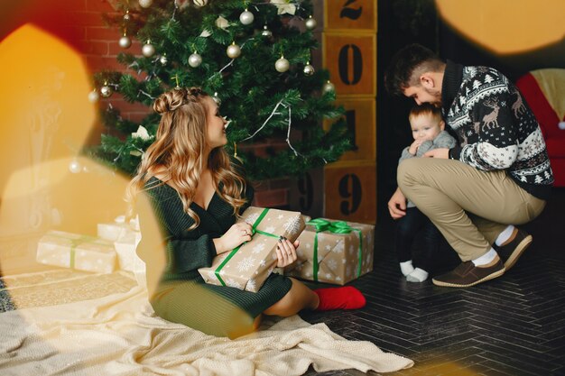 Cute family sitting near Christmas tree