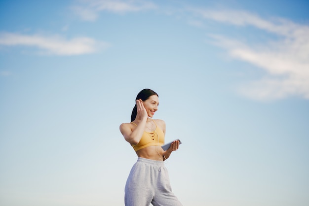 Free photo cute girl with phone training on blue sky