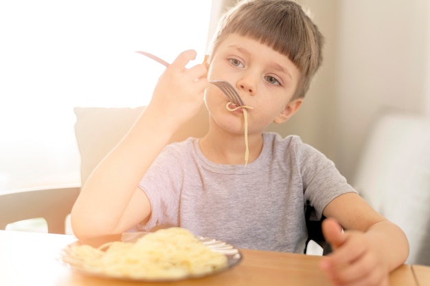 Foto gratuita ragazzo carino mangiare spaghetti