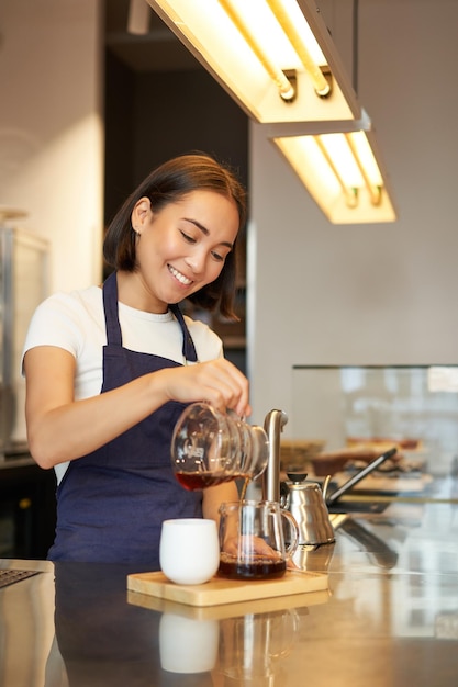 Free photo cute korean barista girl pouring coffee prepare filter batch brew pour over working in cafe