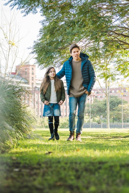 Free photo cute little girl and her father walking together on grass