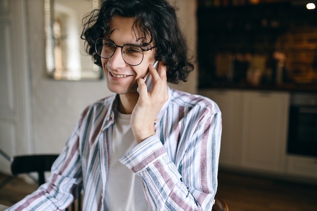 Free photo cute young male in eyeglasses speaking on mobile.