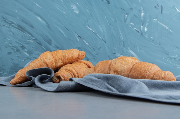 Foto gratuita delizioso croissant su asciugamano, su sfondo blu. foto di alta qualità