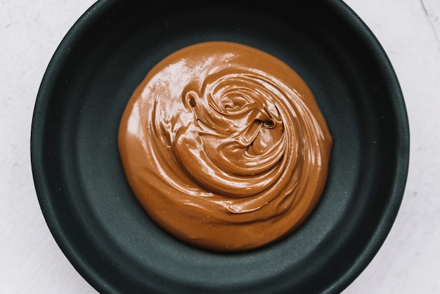 Free photo delicious melted chocolate in black bowl over white background