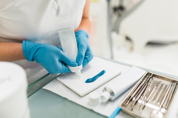 Free photo dental technician's hand removing silicon impression material from tube