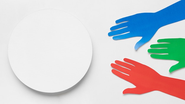 Free photo different colored paper hands next to a white circle