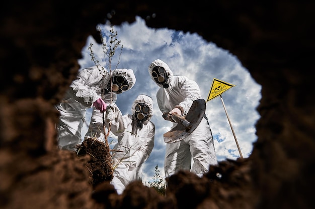 Free photo ecologists digging pit by shovel and planting tree in polluted area