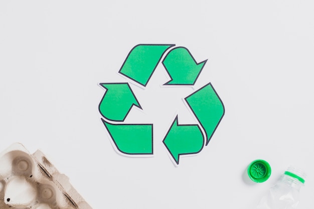 Free photo egg carton and plastic bottle with green recycle icon on white background