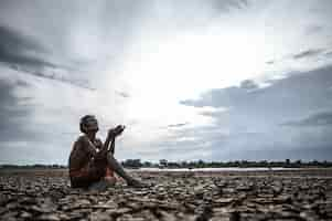 Free photo an elderly man was sitting asking for rain in the dry season, global warming