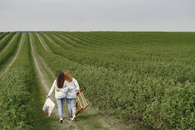 Free photo elegant and beautiful girls painting in a field