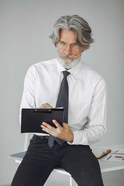 Foto gratuita uomo elegante in ufficio. uomo d'affari in camicia bianca. l'uomo lavora con i documenti.