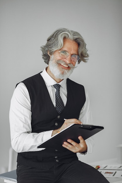 Foto gratuita uomo elegante in ufficio. uomo d'affari in camicia bianca. l'uomo lavora con i documenti.