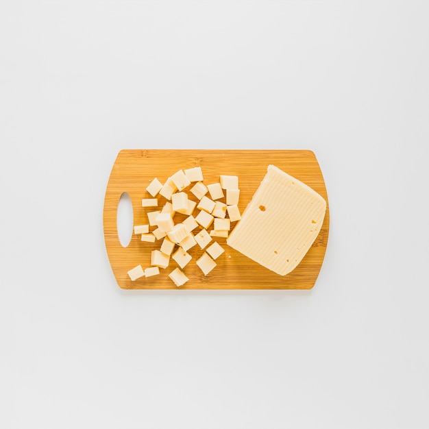 Free photo an elevated view of cheese cubes on wooden chopping board over white background