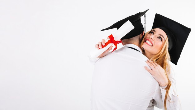 Embracing man and woman with diplomas