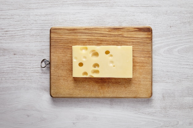 Free photo emmental cheese isolated on board on white brushed farm table