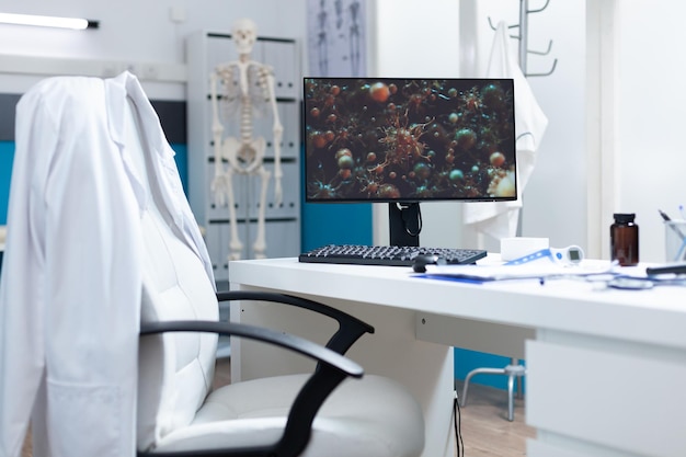 Free photo empty bright medical office having computer on table with coronavirus cell on screen during virus examination. hospital room with nobody in it equipped with professional tools. virus illustration