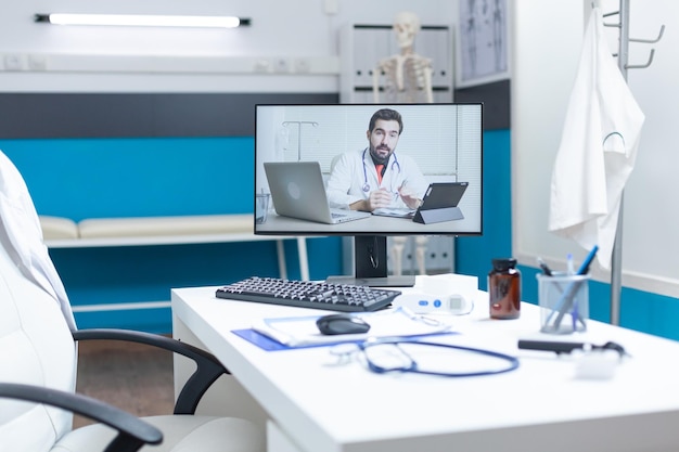 Free photo empty medical office with remote doctor having online discussion during telemedicine videocall meeting conference. computer with telework videoconference call on screen. medicine services support