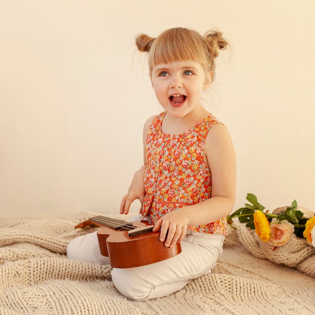 Free photo enthusiastic toddler holding guitar