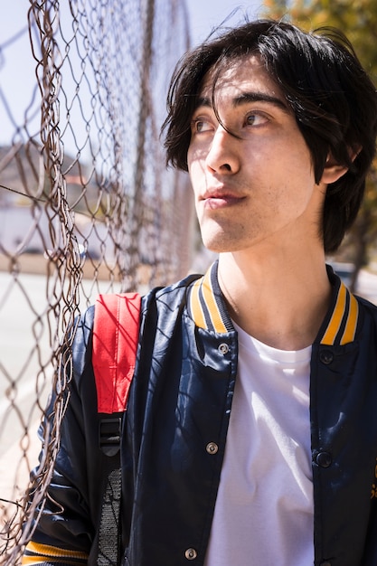 Free Photo ethnic boy looking through fence mesh