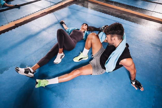 Free photo exhausted couple on floor in gym