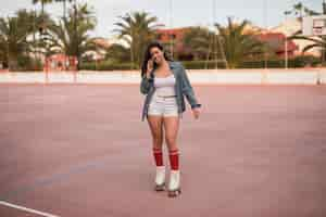 Free photo fashionable young female skater talking on mobile phone