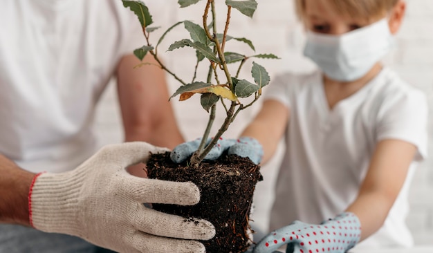 Free photo father and son wearing medical masks and learning about planting