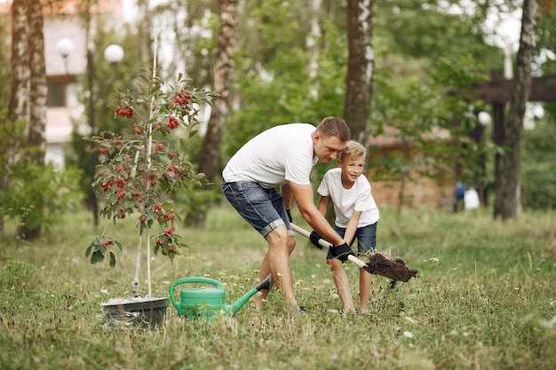 Free photo father with little son are planting a tree on a yard