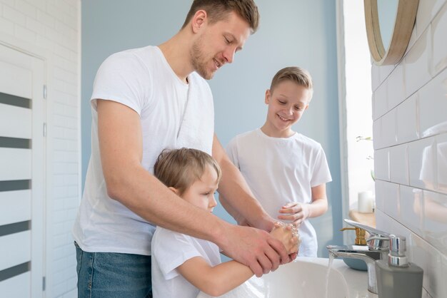 Father with siblings washing hands in the bathroom