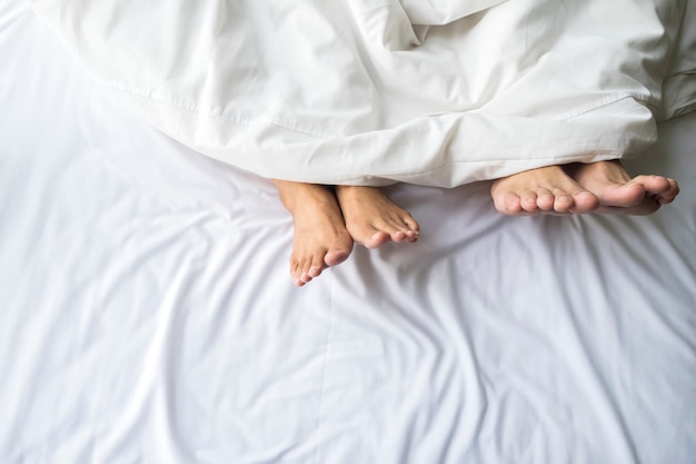 Feet of couple in comfortable bed.