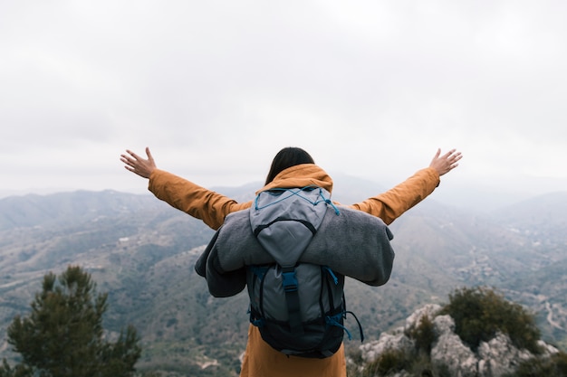 Female backpacker standing on the top of mountain loving the nature