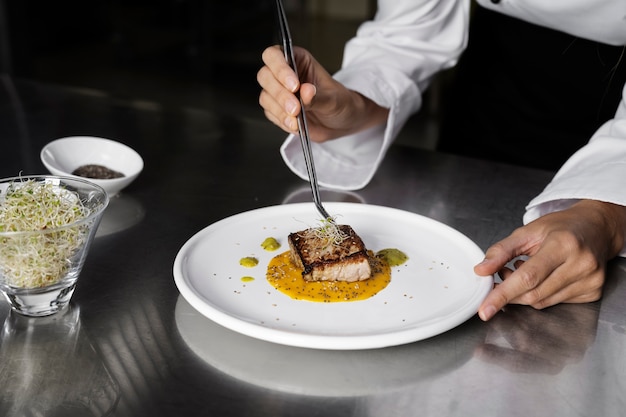 Foto gratuita cuoco unico femminile in cucina che prepara piatto di bistecca