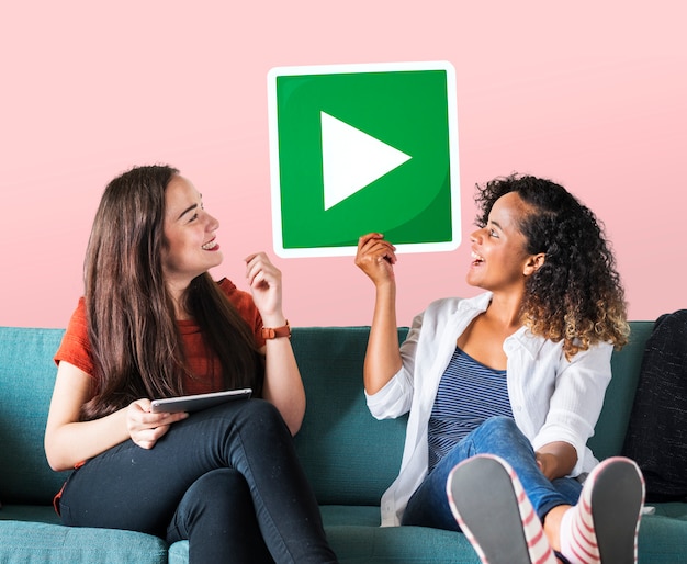 Free photo female friends holding a play button