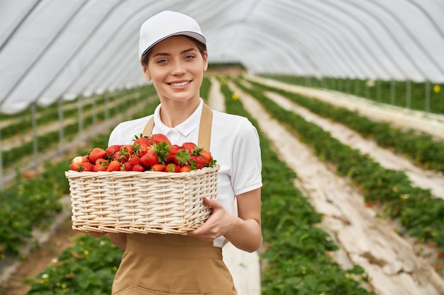 Free Photo female gardener holding wicker basket with strawberries