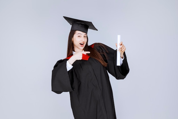 Free photo female graduate student in gown with college certificate feeling happy. high quality photo