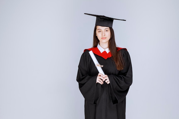 Female graduate student in gown with college certificate posing. High quality photo